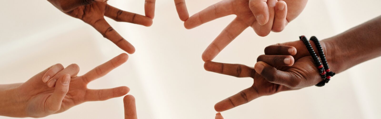 The camera looks up underneath a group of people putting their first two fingers together (connecting peace signs to make a star).